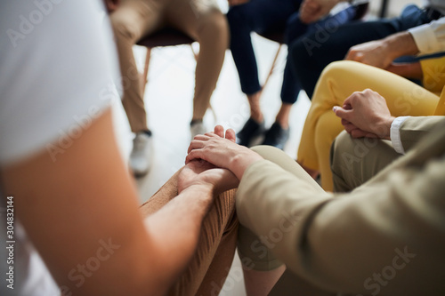 Business people after co-working sit in circle and hold hands together, hope for better work. office background
