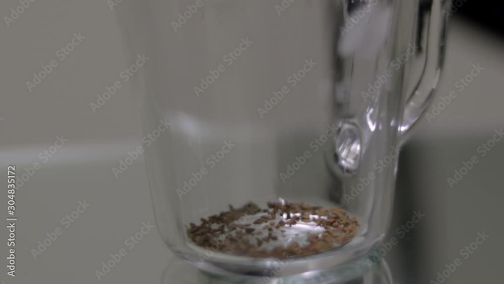 Instant coffee is poured into clear glass on table, close-up
