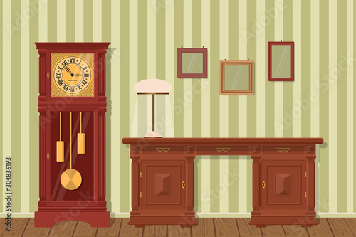 Interior design. Antique desk, grandfather clock, lamp with lampshade and frames on background of striped wallpaper