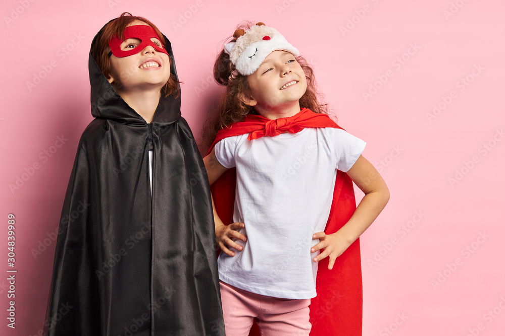 Girl and boy superheroes portrait. Kid boy wearing black cloak, girl in red cloak.
