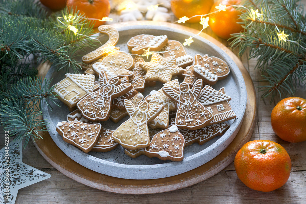 Gingerbread cookies on a concrete tray on a winter background with tangerines, fir branches and a garland.