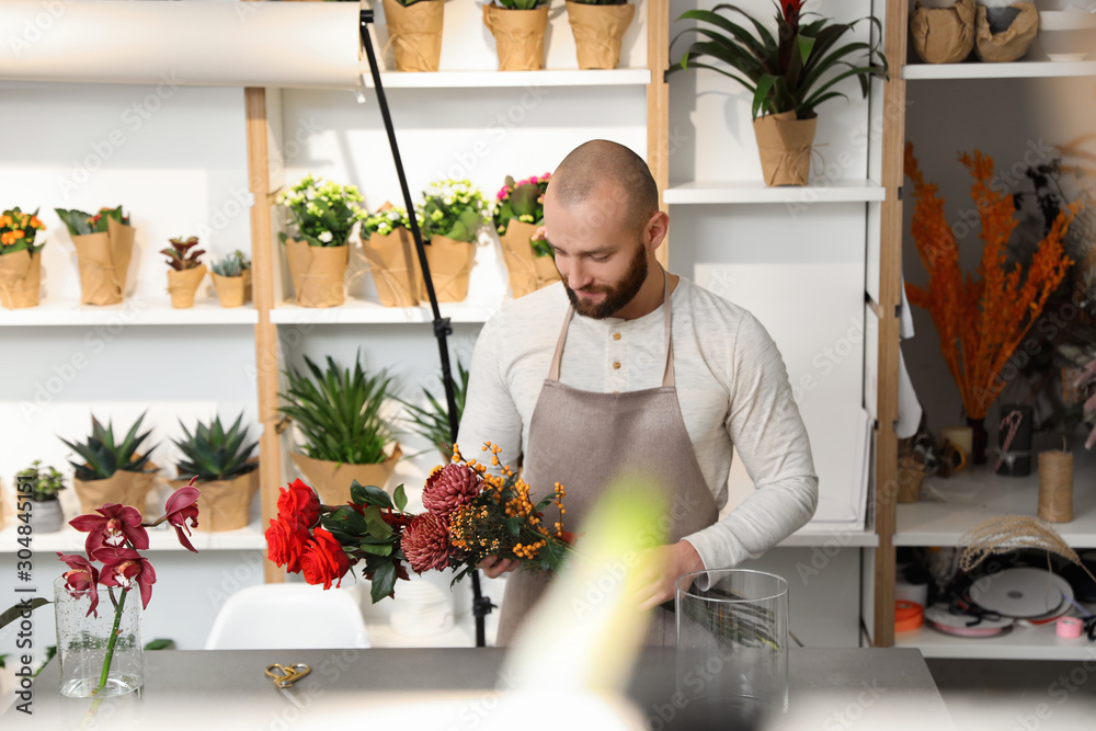 Florist making bouquet with fresh flowers at table in shop