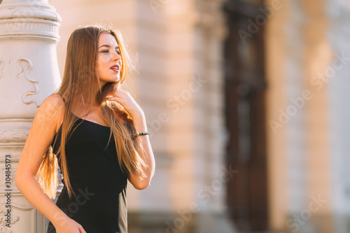 girl with long hair in a black dress near the column. close up.