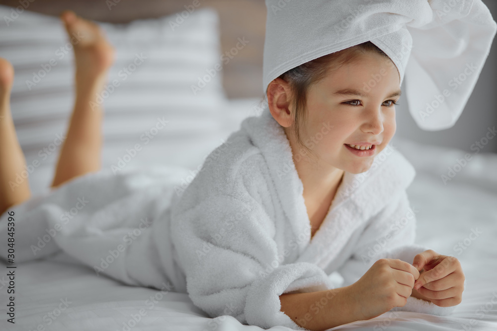 portrait of beautiful child wearing bathrobe and towel, lying on bed and smile. after shower portrait of beautiful child wearing bathrobe and towel, lying on bed and smile. after shower