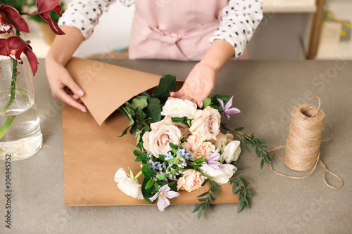 Florist making bouquet with fresh flowers at table, closeup