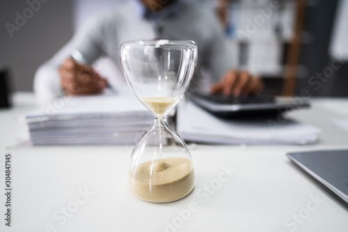 Close-up Of A Hourglass On Desk Stock Photo