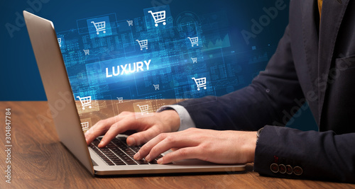 Businessman working on laptop with LUXURY inscription, online shopping concept