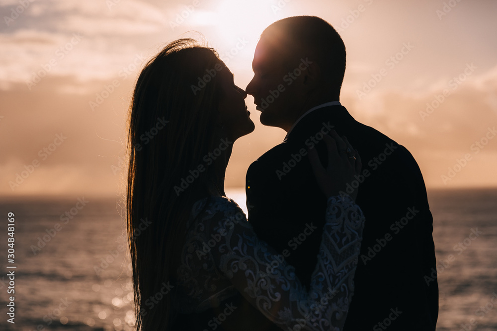 Closeup of newlyweds in each other's arms and kiss. sunset and o