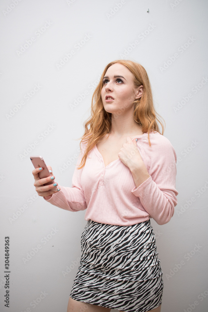 Obraz premium Beautiful long red health hair of young attractive woman isolated white background pink shirt zebra skirt posing mockup advertisement smartphone
