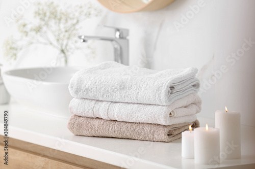 Clean towels and burning candles on counter in bathroom