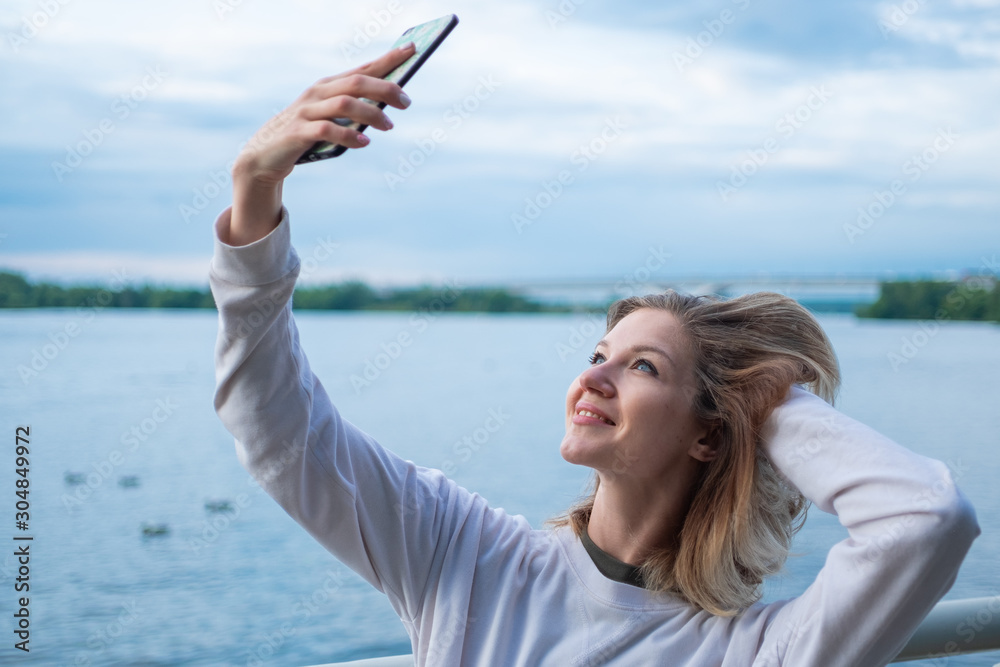Young woman taking selfies on water background