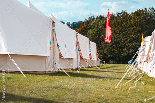 Light creme canvas waterproof tent in a green field on a nice and hot summer day. Blue Clouds, green grass, Child festival tent. photo