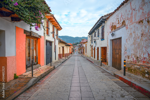 Colorful street of a Mexican town San Cristobal De Las Casas in Chiapas, in the background wooded mountains and a cloudy sky