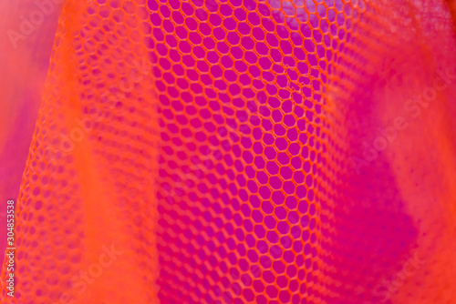 generic background of fishnet in red purple and orange floating under water