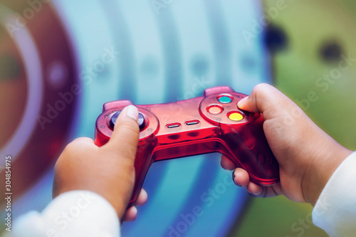 A child playing a shooting genre video game, close-up of the hands holding the controller and pushing buttons. photo