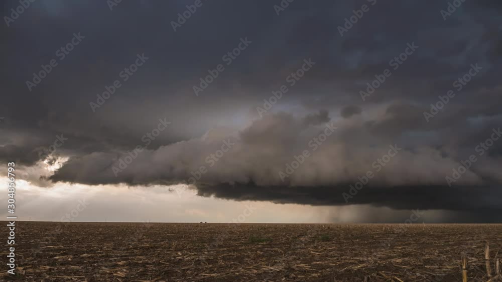 Wall cloud rolling over the landscape in dark dramatic storm during tornado warning.