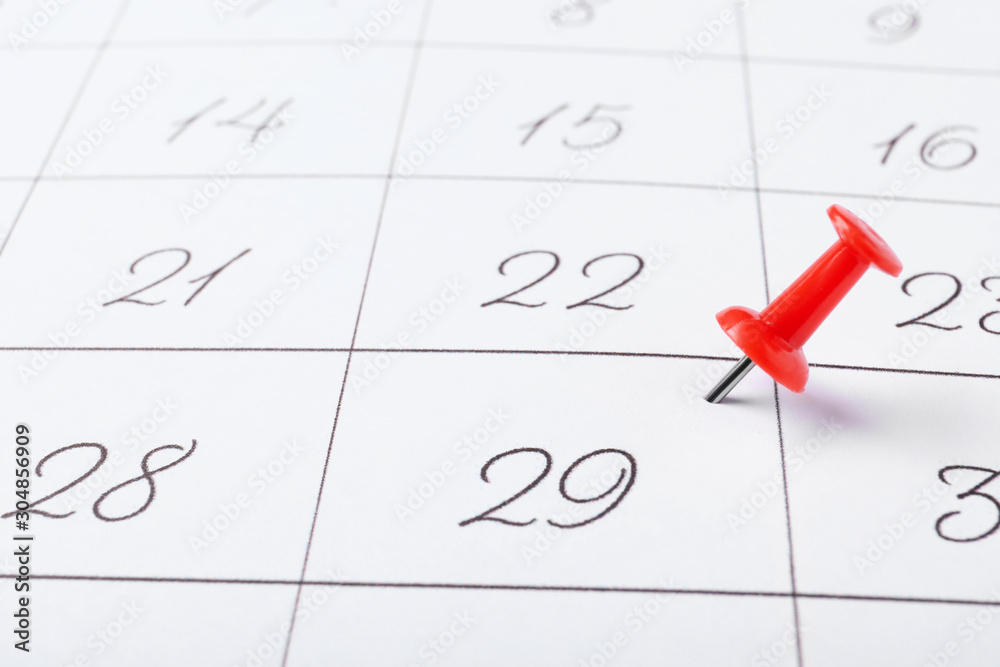 Calendar page marked with drawing pin, closeup