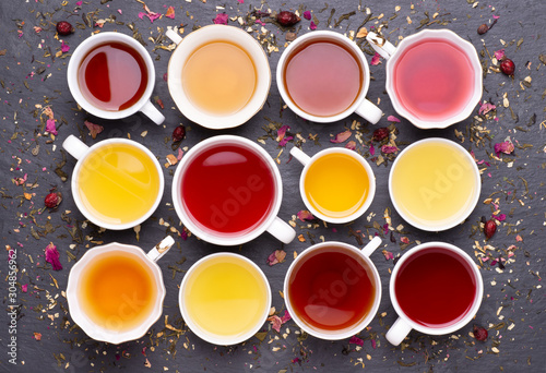 Assortment of tea cups on dark, stone background, top view photo