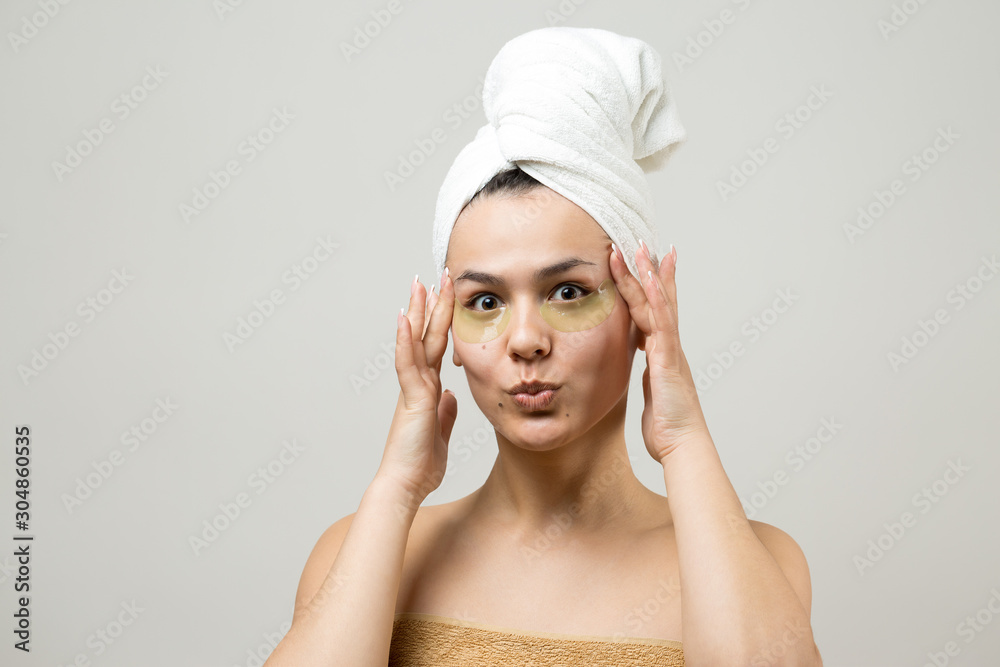Young beautiful girl in a white towel on his head wears collagen gel patches under her eyes. Mask under eyes treatment face. Young beautiful girl in a white towel on his head wears collagen gel patches under her eyes. Mask under eyes treatment face.