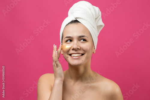 Beauty portrait of woman in white towel on head with gold nourishing mask on face. Skincare cleansing eco organic cosmetic spa relax concept.