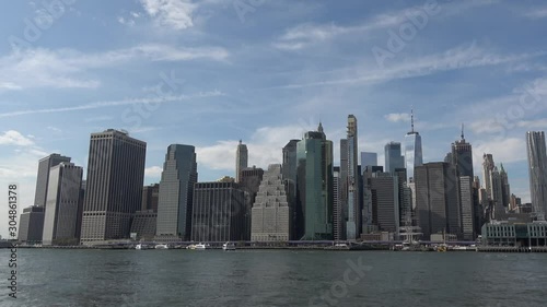 Wallpaper Mural 4K. Skyline of buildings in Manhattan, New York while a tourist ship sails east river under a clear blue sky. New York's tall buildings.Is a very tourist city of the United States. Travel concept. Torontodigital.ca