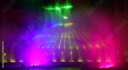 Colorful water fountains. Beautiful laser and fountains show. Large multi colored decorative dancing water jet led light fountain show at night. Dark