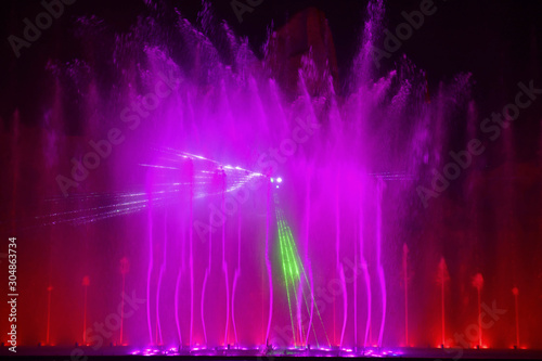 Fototapeta Naklejka Na Ścianę i Meble -  Colorful water fountains. Beautiful laser and fountains show. Large multi colored decorative dancing water jet led light fountain show at night. Dark background.