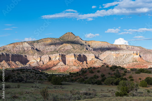 Sunlight spotlights a desert mountain peak with colorful sandstone cliffs at Ghost Ranch, New Mexico