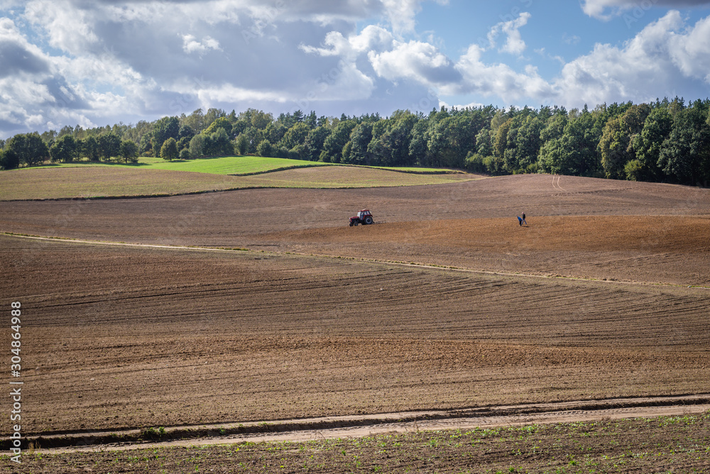 Obraz premium Tractor on field on the border of Ostroda and Ilawa counties, Masuria region in Poland