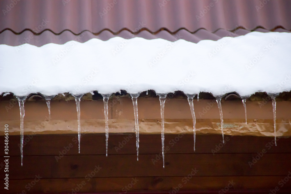 icicles on snow covered roof of a village house in the winter icicles on snow covered roof of a village house in the winter
