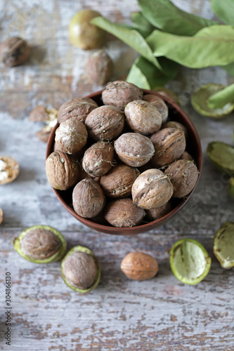 Selective focus. Walnuts in a bowl. The leaves of the walnut tree. Walnuts in a green peel. Harvest walnuts.