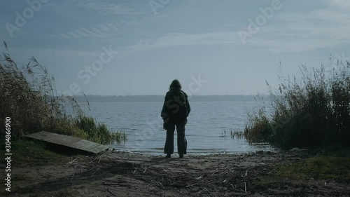 Young woman at the lake looking into the distance. Aerial, dolly shot. photo