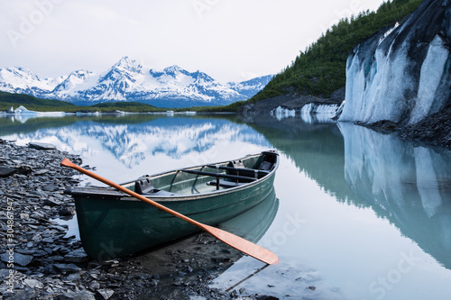 Canoe resting on rock covered ice of Valdez Glacier with icebergs behind. Valdez, Alaska. photo