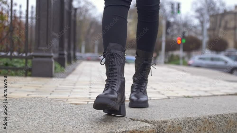 close up of womans black leather boots with laces walking down the street close up of womans black leather boots with laces walking down the street