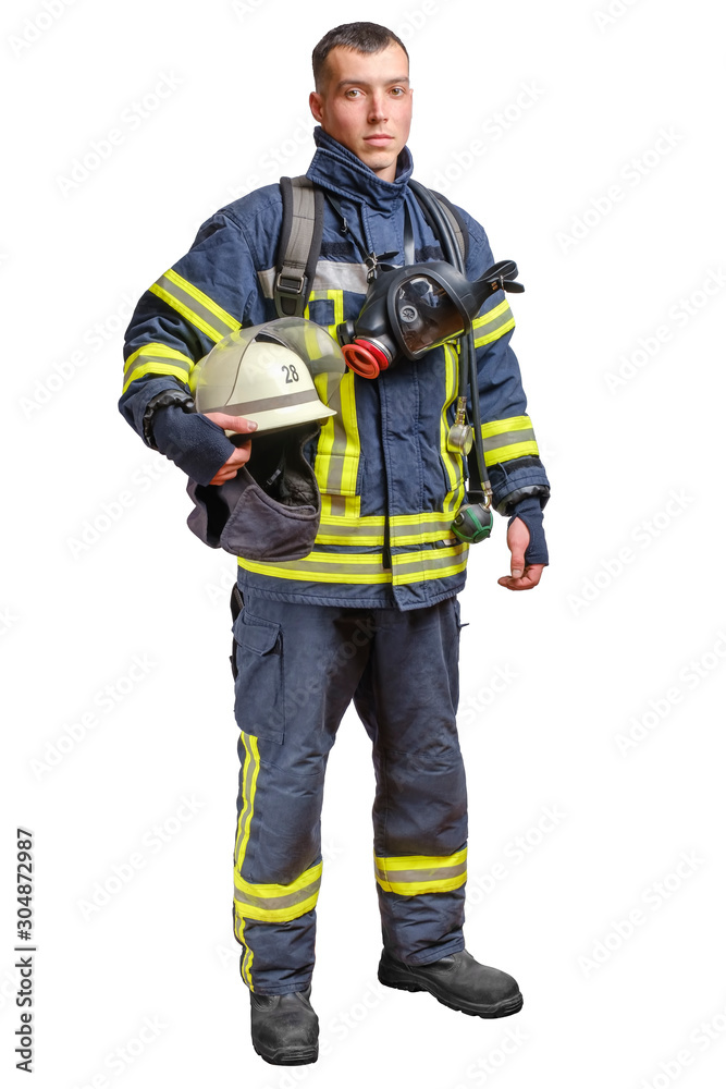 A young brave fireman in a fireproof uniform stands and looks at the camera with a helmet in his hands. A young brave fireman in a fireproof uniform stands and looks at the camera with a helmet in his hands.