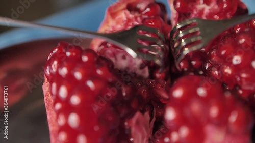 Dynamic, cinematic, close-up of pomegranate and opening of it using surgical volkmann retractor showing the inside part of a fruit. Filmed in slow motion photo