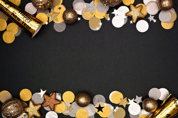 New Years Eve double border of confetti, decorations and noisemakers. Top view over a black background.