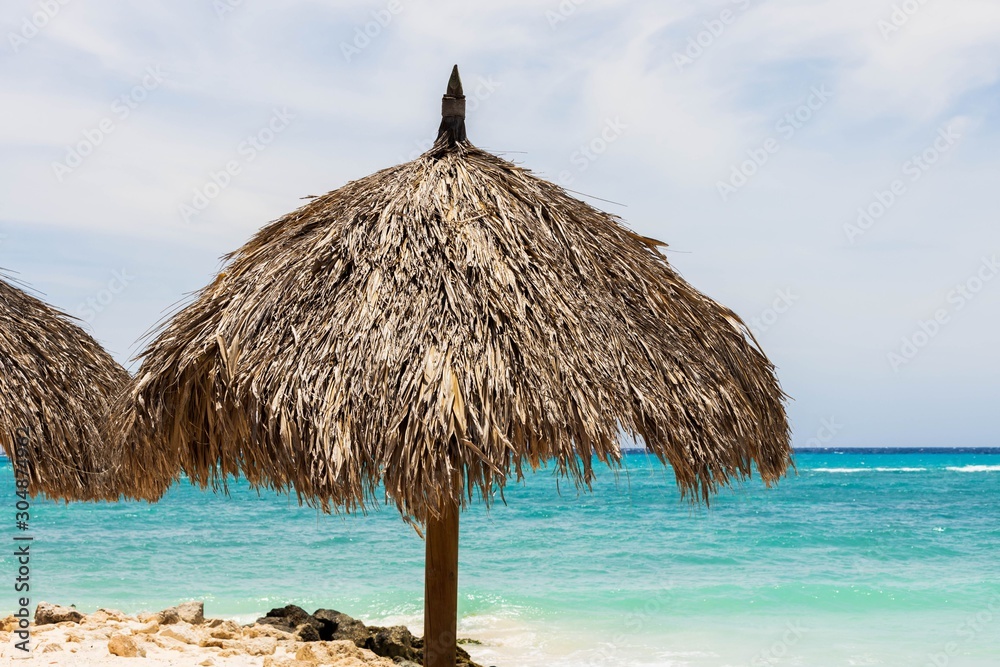 Beautiful view of white sand beach with sun umbrellas and sunbeds. Eagle beach. Aruba island.