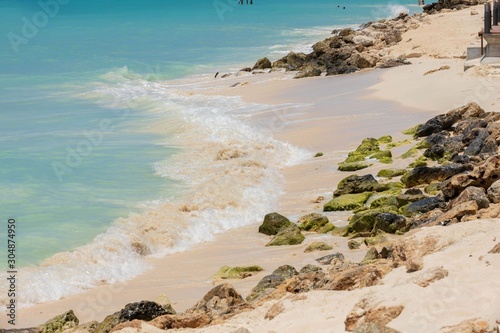 White sand beach and turquoise waves. Turquoise sea water and blue sky. Eagle Beach of Aruba Island. Beautiful backgrounds.