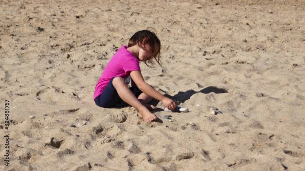 Little girl playing with stones in the sand Little girl playing with stones in the sand