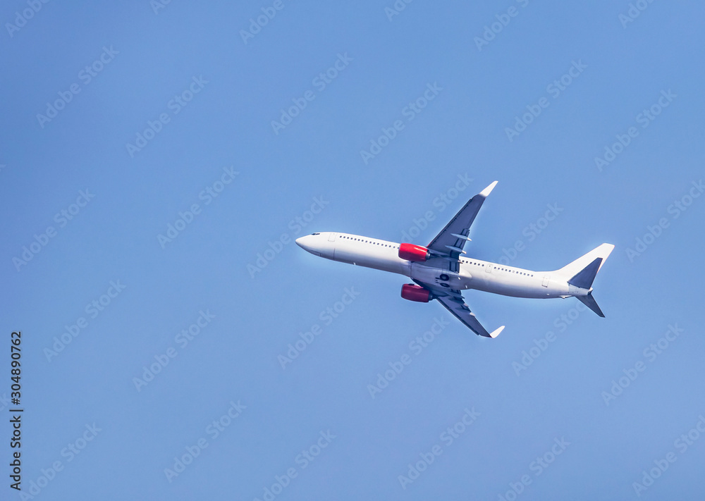 White commercial airplane flying away in to clear sky travel destinations concept. White commercial airplane flying away in to clear sky travel destinations concept.