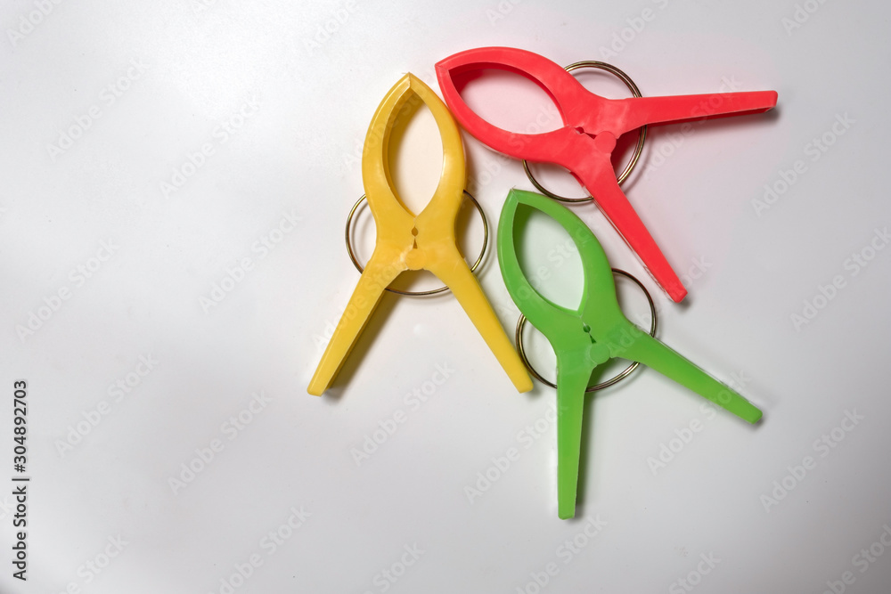 Three large cloth clips, various colors placed on a white background. Three large cloth clips, various colors placed on a white background.