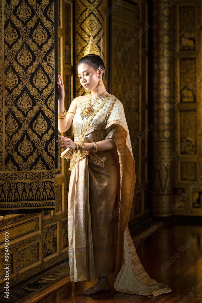 Beautiful Thai girl in traditional Thai national costume Standing by the window of a beautiful golden Thai house