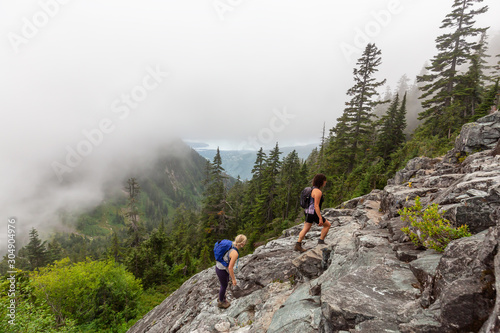 Adventurous Girl is hiking in beautiful green woods in the mountains during a cloudy summer morning. Taken on Crown Mountain, North Vancouver, BC, Canada. © edb3_16