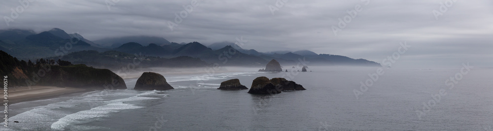 Cannon Beach, Oregon, United States. Beautiful Aerial Panoramic View of the Rocky Pacific Ocean Coast during a cloudy summer sunrise.