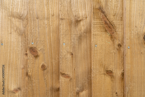 New wooden fence texture background in brown with iron nails