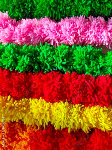 Wool Craft - Background of multicolored pom poms string arranged sideby side photo