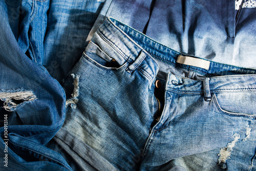 Fotografija Pile of faded and ripped denim shorts and jeans in sunlight / Second-hand sustai