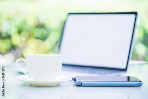 Coffee cup and laptop at office with smartphone