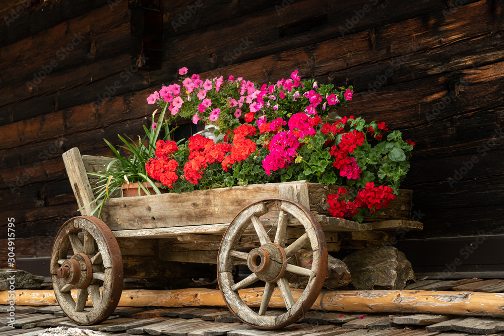 An old wooden cart with beautiful flowers on the roof of an old house